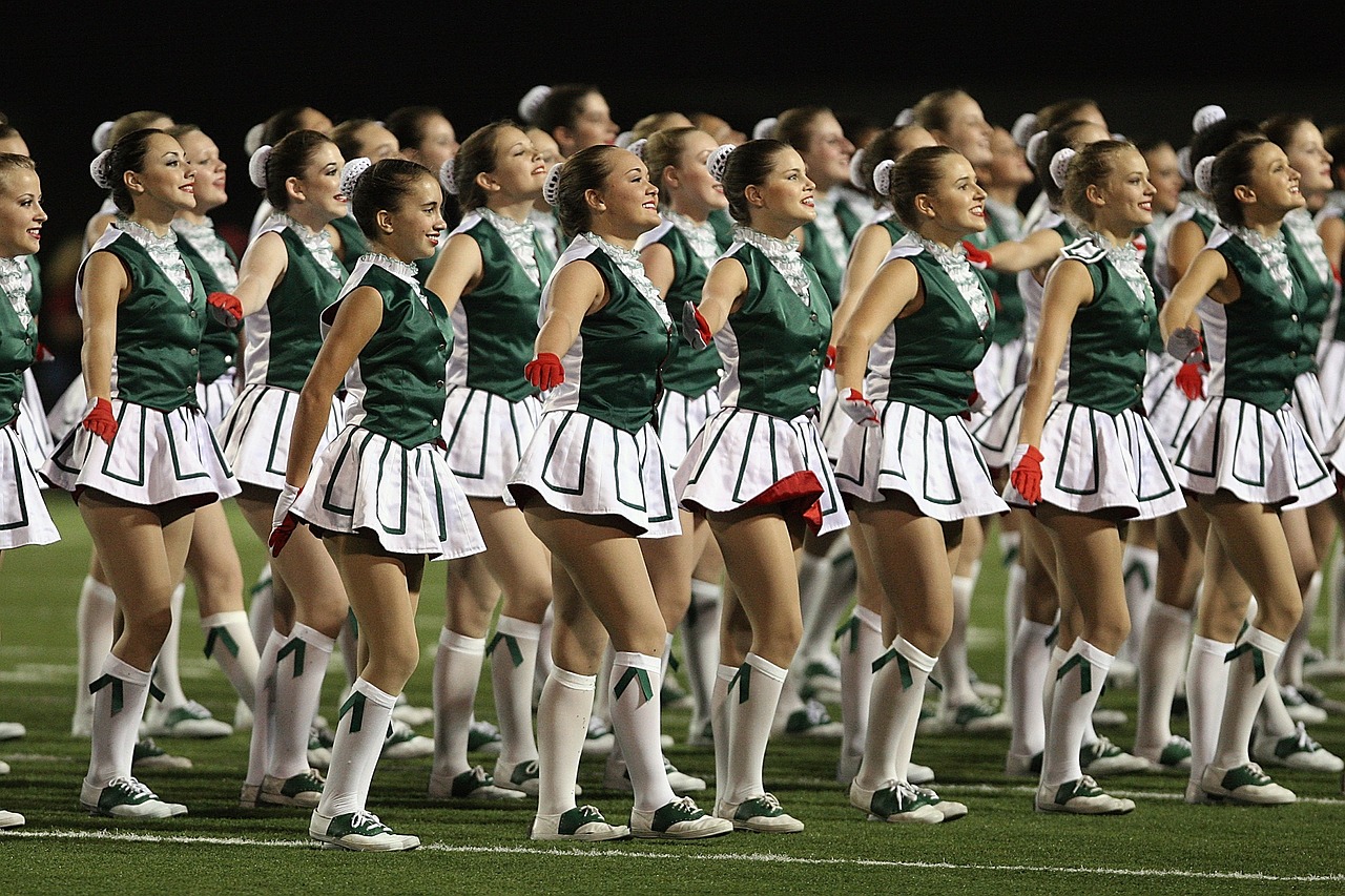 High school drill team performing in uniform on a football field.