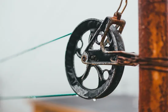 Close-up of a pulley system with a metal wheel and a rope.